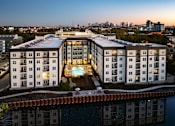 Thumbnail 2 of 27 - A modern apartment building with a pool in the middle of it.