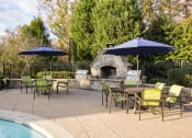 Thumbnail 4 of 13 - Poolside patio with tables, umbrellas and a stone fireplace
