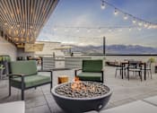 Thumbnail 12 of 30 - a patio with a fire pit and tables and chairs with mountains in the background