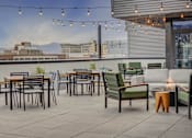 Thumbnail 11 of 30 - a rooftop patio with tables and chairs and a view of the city