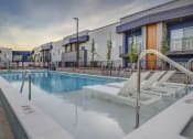 Thumbnail 8 of 26 - apartments with a pool and lounge chairs at dusk