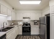 Thumbnail 46 of 51 - A kitchen with white cabinets and a black fridge.