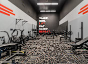 Thumbnail 17 of 51 - a workout room with weights and cardio machines and a motivational wall in the background