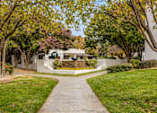 Thumbnail 25 of 51 - a sidewalk leading to a house with trees and a fountain