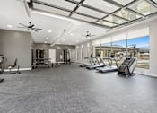 Thumbnail 14 of 23 - A spacious gym with treadmills, elliptical machines, and a fan.