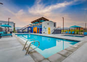 Thumbnail 13 of 34 - a swimming pool with a building in the background at dusk