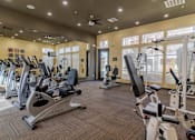 Thumbnail 20 of 21 - A gym with a variety of equipment including treadmills, stationary bikes, and weight machines.