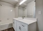 Thumbnail 40 of 45 - A white bathroom with a tub, sink, and mirror.