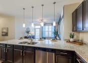 Thumbnail 7 of 26 - A kitchen with dark brown cabinets and a granite countertop.