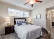 Thumbnail 4 of 26 - A bedroom with a bed, two nightstands with lamps, and a ceiling fan.