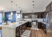 Thumbnail 2 of 26 - A modern kitchen with dark brown cabinets and stainless steel appliances.