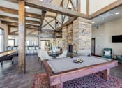 Thumbnail 21 of 26 - A pool table in a room with wooden beams on the ceiling.