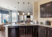 Thumbnail 19 of 31 - a kitchen with dark cabinets and a counter top with a sink