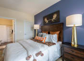 Thumbnail 21 of 31 - bedroom with blue accent wall and white bed with pillows and orange pillows on