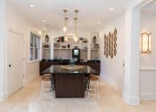 Thumbnail 23 of 33 - a kitchen with white walls and tiles flooring and a large center island with a black counter at Westmount at Ashwood, Georgia