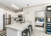Thumbnail 1 of 33 - a kitchen with a breakfast bar and a bedroom in the background at Westmount at Ashwood, Georgia
