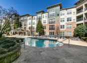 Thumbnail 19 of 33 - a swimming pool with chaise lounge chairs and trees in front of an apartment building at Westmount at Ashwood, Atlanta, GA, 30338