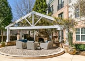 Thumbnail 18 of 33 - a patio with a fireplace and seating area in front of a brick building at Westmount at Ashwood, Atlanta