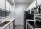 Thumbnail 3 of 27 - a kitchen with white cabinets and black appliances