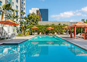 Thumbnail 8 of 32 - A swimming pool surrounded by orange umbrellas and lounge chairs.