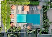 Thumbnail 4 of 32 - A swimming pool surrounded by greenery and concrete.