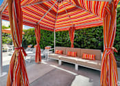 Thumbnail 6 of 32 - A patio with a striped canopy and a couch.