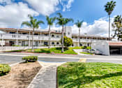 Thumbnail 1 of 14 - A building with a white fence and a car parked in front.