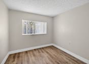 Thumbnail 20 of 31 - A room with wooden flooring and a window with blinds.