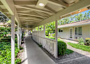 Thumbnail 11 of 15 - A long white porch with a white railing and a white house with a green lawn.