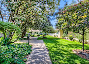 Thumbnail 14 of 15 - A pathway in a garden with a house in the background.