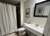Thumbnail 5 of 14 - A bathroom with a toilet, sink, and shower curtain.
