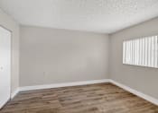 Thumbnail 18 of 31 - A room with wooden flooring and a window with blinds.