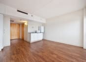 Thumbnail 5 of 27 - an empty living room and kitchen with wood flooring and white walls