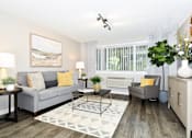 Thumbnail 1 of 21 - A living room with a grey couch, a coffee table, and a painting on the wall.