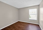 Thumbnail 24 of 41 - Empty room with a window and wooden floor.