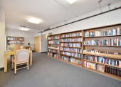 Thumbnail 21 of 27 - a library with a table and chairs and shelves of books