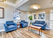Thumbnail 4 of 14 - A living room with blue chairs and a wooden coffee table.