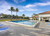 Thumbnail 9 of 31 - A pool with sun loungers and palm trees in the background.