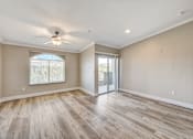 Thumbnail 16 of 22 - Open living room with patio doors and ceiling fan at Borgata Condominiums Apartments, Las Vegas, 89103