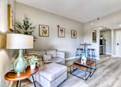 Thumbnail 5 of 14 - A living room with a grey couch, a wooden coffee table, and a green vase on a wooden table.