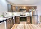 Thumbnail 6 of 14 - A modern kitchen with wooden cabinets and stainless steel appliances.