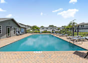 Thumbnail 28 of 41 - A swimming pool surrounded by lounge chairs and buildings in the background.