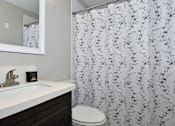 Thumbnail 13 of 21 - A white sink with a gold faucet and a toilet in a bathroom.