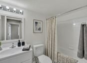 Thumbnail 17 of 27 - A bathroom with a white toilet, sink, and shower area.