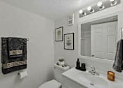 Thumbnail 19 of 27 - A bathroom with a white toilet, sink, and mirror.