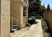 Thumbnail 4 of 14 - A concrete staircase with a metal railing leads up to a building.