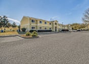Thumbnail 10 of 29 - A large yellow building with a parking lot in front.