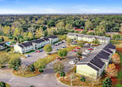 Thumbnail 12 of 14 - A large building complex with a parking lot in front.