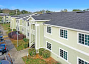 Thumbnail 7 of 14 - A row of houses with green siding and white trim.