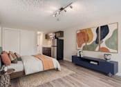 Thumbnail 4 of 15 - A bedroom with a bed, a nightstand, and a painting on the wall.